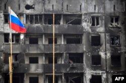 Bendera nasional Rusia berkibar di gedung-gedung yang hancur di Mariupol pada 12 April 2022, saat pasukan Rusia mengintensifkan aksi untuk merebut kota pelabuhan yang strategis itu. (Foto: AFP)