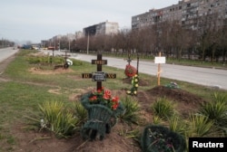 Graves of civilians killed during Ukraine-Russia war are seen next to apartment buildings in the southern port city of Mariupol, Ukraine, April 10, 2022.