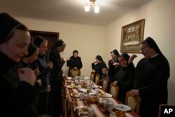 Nuns make prayers after eating dinner, at the Hoshiv Women Monastery, where they have been taking in internally displaced families fleeing the war, in Ivano-Frankivsk region, western Ukraine, April 6, 2022. (AP Photo/Nariman El-Mofty)