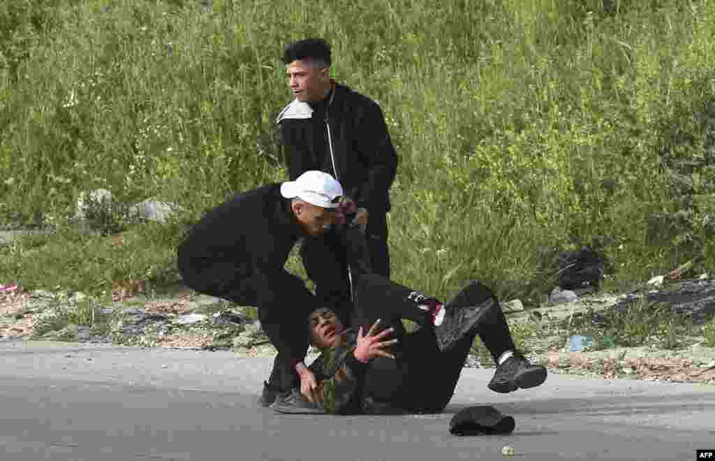 Dua warga Palestina membantu seorang pemuda yang terluka dalam bentrokan dengan pasukan keamanan Israel di kota Nablus, wilayah Tepi Barat yang diduduki Israel (11/4). (Foto: AFP)