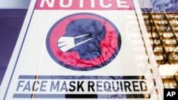 FILE - A sign requiring masks as a precaution against the spread of the coronavirus is seen on a store front in Philadelphia, Feb. 16, 2022. 