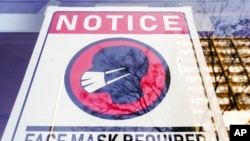 FILE - A sign requiring masks as a precaution against the spread of the coronavirus is seen on a store front in Philadelphia, Feb. 16, 2022. The city on April 18, 2022, reimposed a mask mandate in settings including restaurants, schools and businesses following a rise in local COVID-19 cases, only to reverse course days later.