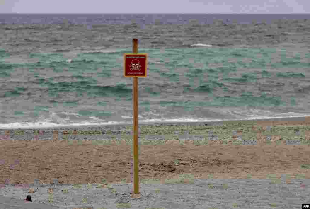 Una fotografía tomada el 7 de abril de 2022 muestra una señal de advertencia que dice &quot;Peligro, minas&quot; en una playa de la ciudad de Odessa.