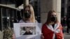 FILE - A woman holds a sign during a protest in Warsaw, Poland, May 24, 2021, against the detention of Belarusian blogger Raman Pratasevich, who was arrested after a passenger plane that he was on was diverted and forced to land Minsk, Belarus.