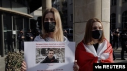 FILE - A woman holds a sign during a protest in Warsaw, Poland, May 24, 2021, against the detention of Belarusian blogger Raman Pratasevich, who was arrested after a passenger plane that he was on was diverted and forced to land Minsk, Belarus.