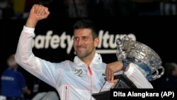 Novak Djokovic of Serbia gestures as he holds the Norman Brookes Challenge Cup after defeating Stefanos Tsitsipas of Greece in the men's singles final at the Australian Open tennis championship in Melbourne, Australia, Sunday, Jan. 29, 2023. (AP Photo/Dita Alangkara)