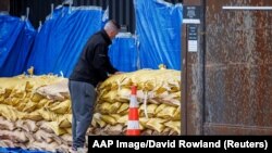 A man stacks sandbags to protect a warehouse from a sub-tropical low-pressure system in Auckland, New Zealand, Feb. 12, 2023.