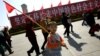 资料照：一个男孩手举红旗走过天安门广场上竖立的走中国特色社会主义道路的标语牌。（2007年10月9日）