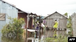 Des habitants du quartier Belle Souvenir devant leur maison submergée par les eaux à Sambava le 21 janvier 2023, suite au passage d'un cyclone le 19 janvier 2023.