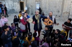 Mohammed al-Amodi (mengenakan kostum Ali Baba), menyanyi dan menari untuk menghibur anak-ana di Rafah, Jalur Gaza selatan, 19 Januari 2023. (REUTERS/Ibraheem Abu Mustafa)