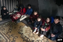 Members of a Syrian family made homeless by a deadly earthquake rest in a make-shift shelter, in the Afrin region of Syria's rebel-held northern Aleppo province, on Feb. 8, 2022.