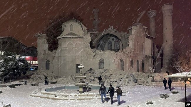 People walk next to a mosque destroyed by an earthquake in Malatya, Turkey, Feb. 6, 2023.