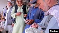 Afghan money exchange dealers wait for customers at a money exchange market, following banks and markets reopening after the Taliban took over in Kabul, Sept. 4, 2021.