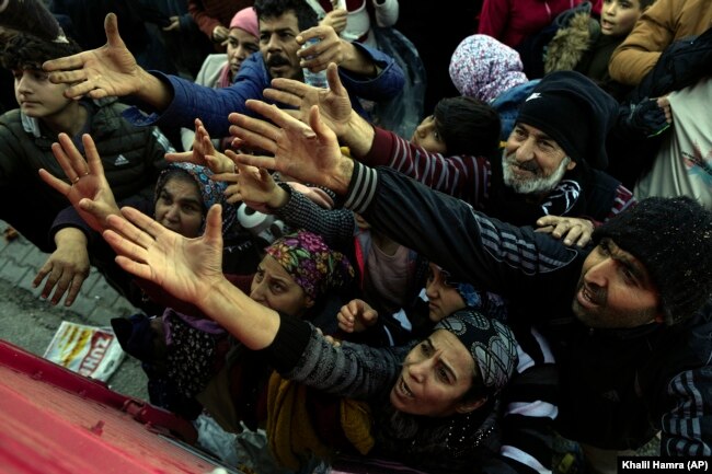 Volunteers distribute aid to people in Antakya, southern Turkey, Wednesday, Feb. 8, 2023. (AP Photo/Khalil Hamra)