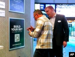 An employee at the Ocean Casino Resort, right, in Atlantic City, New Jersey, helps a customer use a cellphone to scan a sports betting code, Feb. 6, 2023.