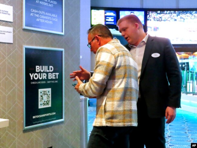 An employee at the Ocean Casino Resort, right, in Atlantic City, New Jersey, helps a customer use a cellphone to scan a sports betting code, Feb. 6, 2023.