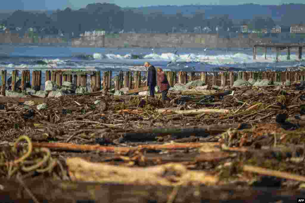 Луѓе шетаат меѓу дрва и остатоци од бура на плажата Рио Дел Мар во Аптос, Калифорнија, јануари. 17, 2023 година.