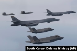 In this photo provided by South Korean Defense Ministry, U.S. Air Force B-1B bombers, center, F-22 fighter jets and South Korean Air Force F-35 fighter jets, bottom, fly during a joint air drill in South Korea, Jan. 1, 2023.