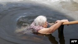 Valentyna Rudyk, 86, bathes in the icy Siverskyi Donets River next to the Sviatohirsk Orthodox Christian Monastery in Svyatohirsk, near the front line, Donetsk region, Ukraine, on Jan. 19, 2023,