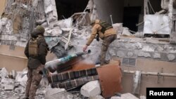 Ukrainian servicemen remove a grad rocket in a damaged house after an attack in Kherson, Jan. 29, 2023. 