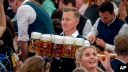 Seorang pramusaji membawa bir di salah satu tenda bir pada hari pembukaan festival bir Oktoberfest ke-187 di Munich, Jerman, 17 September 2022. (AP/Michael Probst)