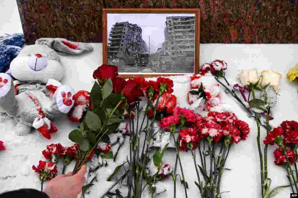 Едно лице положува цвеќе во спомен на загинатите во рускиот ракетен напад викендот во станбен блок во украинскиот град Днeпар, на споменикот на познатата украинска поетеса Лесија Украинка во Москва, Русија. (Фото на АФП)