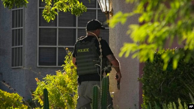 FILE - A police officer unholsters his gun while investigating the stabbing death of Las Vegas Review-Journal investigative reporter Jeff German, in Las Vegas, Sept. 7, 2022.