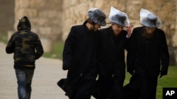 FILE - Ultra Orthodox Jewish men wear plastic bags over their hats, as they walk outside Jerusalem's old city, Dec. 12, 2010.