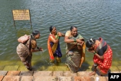 FILE - Huvakka Bhimappa (L) along with other former 'devadasis' women cleanse themselves in a pond before visiting Yellamma Devi temple in Savadatti of Belgaum district, in India's Karnataka state, Sept. 21, 2022.