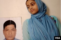 A 17-year-old girl is seen at her Dhaka home with a photo of her father, Ismail Hossain Baten. Since Baten was picked up by members of a security agency in 2019, his family has been running from pillar to post in search of him. (Enam Islam for VOA)