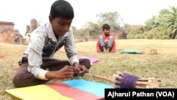 Children are getting ready to fly kites in an Indian village. With the kites they also have Chinese manjha on their kite flying reels.