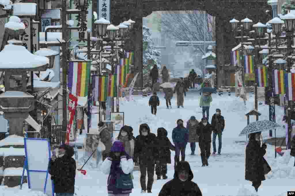 Orang-orang berjalan di atas jalanan bersalju saat mengunjungi Kuil Zenkoji di Nagano, Jepang. (AFP)