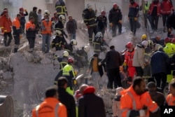 Petugas pemadam kebakaran dan petugas penyelamat mencari korban selamat di reruntuhan bangunan yang hancur di Adana, Turki selatan, 8 Februari 2023. (Foto: AP)