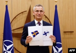 Sekretaris Jenderal NATO Jens Stoltenberg menunjukkan dokumen aplikasi yang diserahkan oleh Duta Besar Finlandia untuk NATO Klaus Korhonen dan Duta Besar Swedia untuk NATO Axel Wernhoff di Brussels, pada 18 Mei 2022. (Foto: AFP)