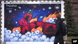 People look at a new postage stamp design depicting the burning Kremlin as they pass by a City Hall in central Kyiv, Ukraine, Jan. 27, 2023. 