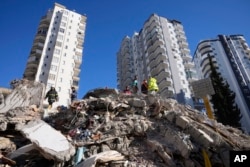 FILE - Emergency teams search for people in the rubble of a destroyed building in Adana, southern Turkey, Feb. 7, 2023