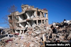 A man sits at his destroyed house in Kahramanmaras, southern Turkey, Wednesday, Feb. 8, 2023. (AP Photo/Hussein Malla)