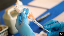 FILE - A nurse prepares a syringe of a COVID-19 vaccine at an inoculation station in Jackson, Mississippi, July 19, 2022.