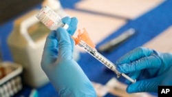 FILE - A nurse prepares a syringe of a COVID-19 vaccine at an inoculation station in Jackson, Miss., July 19, 2022. U.S. health officials are proposing a simplified approach to COVID-19 vaccinations that would be similar to the annual flu shot. 