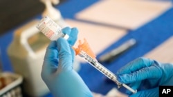 FILE - A nurse prepares a syringe of a COVID-19 vaccine at an inoculation station in Jackson, Miss., July 19, 2022.