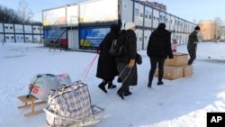 People carry their belongings at a modular town for refugees from war-hit Ukrainian regions in Lviv, Ukraine, Feb. 9, 2023.