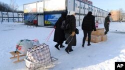 Las personas llevan sus pertenencias en una ciudad modular para refugiados de las regiones ucranianas afectadas por la guerra en Lviv, Ucrania, el 9 de febrero de 2023.