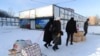 People carry their belongings at a modular town for refugees from war-hit Ukrainian regions in Lviv, Ukraine, Feb. 9, 2023.
