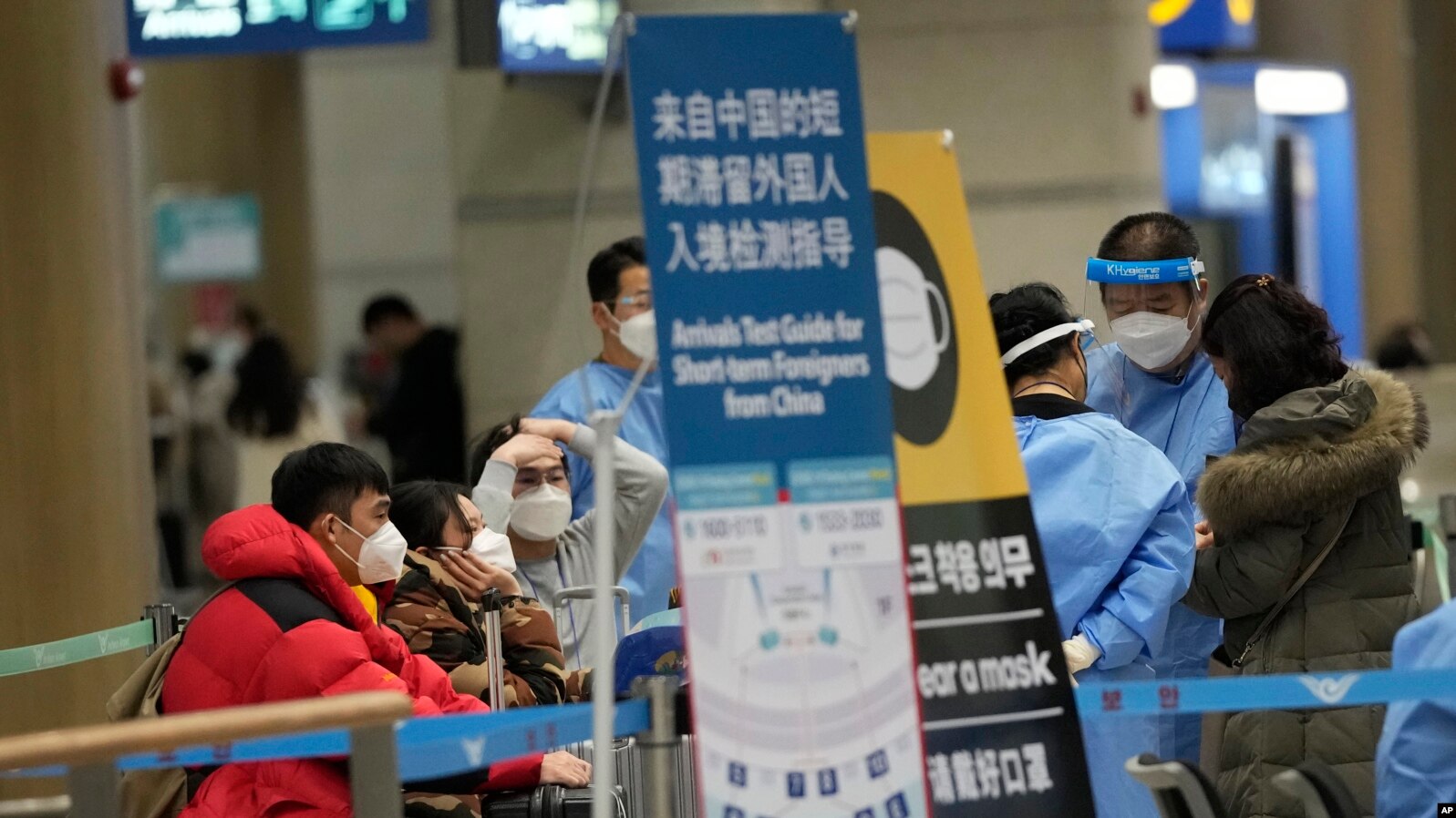 抵达韩国仁川国际机场的中国乘客等待前往入境测试中心。（美联社2023年1月14日）