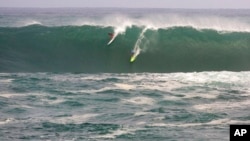 FILE - Jamie Mitchell, right, and Ross Clarke-Jones, both of Australia, surf in the Eddie Aikau big-wave surfing contest in Waimea Bay near Haliewa, Hawaii, on Feb. 25, 2016.