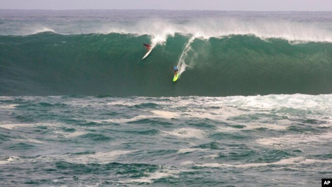 FILE - Jamie Mitchell, right, and Ross Clarke-Jones, both of Australia, surf in the Eddie Aikau big-wave surfing contest in Waimea Bay near Haliewa, Hawaii, on Feb. 25, 2016.