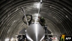 FILE - A Rafale jet fighter pilot checks and prepares his aircraft with the help of an army mecanic before leaving for a four-month mission to protect the airspace of the Baltic States, in southwestern France, on Nov. 25, 2022.