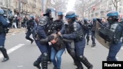 Petugas kepolisian tampak menahan seorang demonstran dalam aksi protes menentang rencana menaikkan batas usia pensiun di Prancis. Aksi tersebut digelar di Paris, pada 19 Januari 2023. (Foto: Adrien AdcaZz via Reuters)