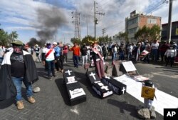 Demonstrators block a highway with mock coffins carrying the names of Peruvian President Dina Boluarte and congresspeople in Arequipa, Peru, Jan. 19, 2023.