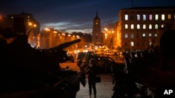 A woman stands in front of a display of destroyed Russian tanks and armored vehicles in downtown Kyiv, Ukraine, Jan. 20, 2023.